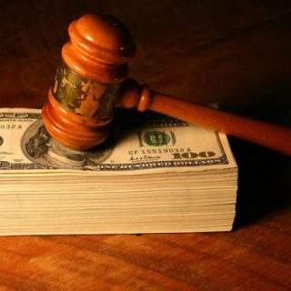 gavel resting on a stack of hundred dollar bills