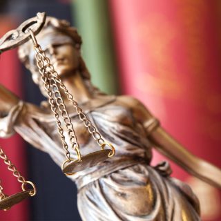 closeup of blind lady justice statue & books in the background
