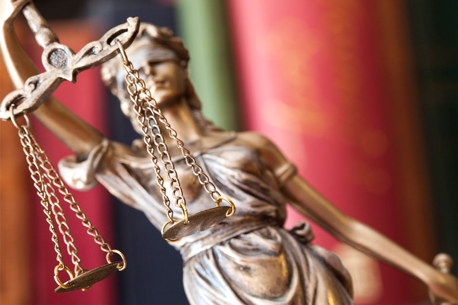 closeup of blind lady justice statue & books in the background