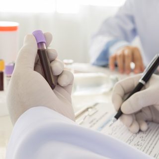 gloved hand holding a blood sample and documenting it