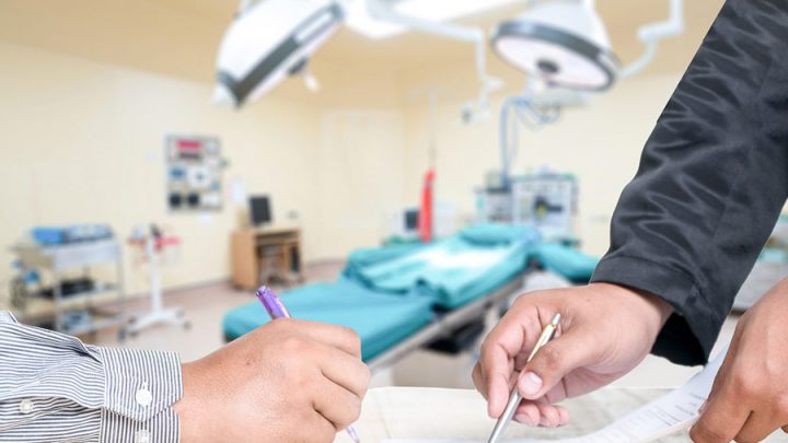 signing a document with medical device equipment in the background