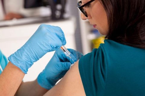 Nurse at pharmacy clinic giving flu shot to patient