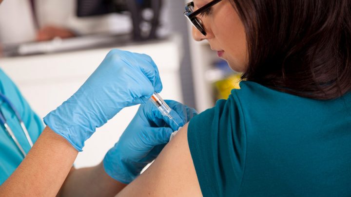 Nurse at pharmacy clinic giving flu shot to patient