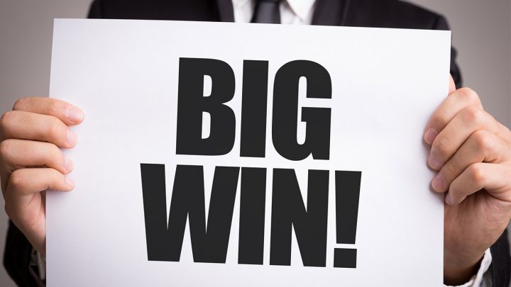 Man in suit holding a paper that read "Big Win!"