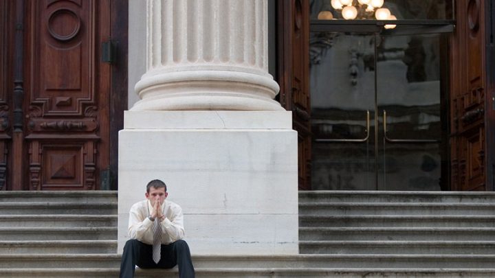 Upset man setting on steps of courthouse