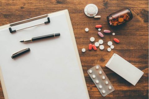 clipboard and pills on top of a table