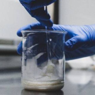 Pharmacist with blue gloves and glass jar