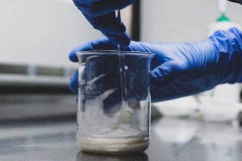 Pharmacist with blue gloves and glass jar