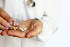 Person pouring pills into their hand.