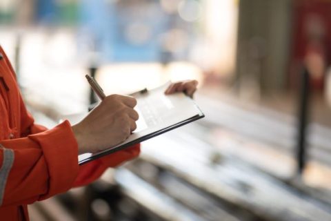 Inspector in orange holding clipboard