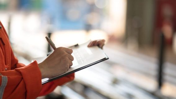 Inspector in orange holding clipboard