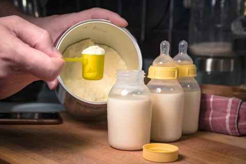 Person scooping infant formula from can