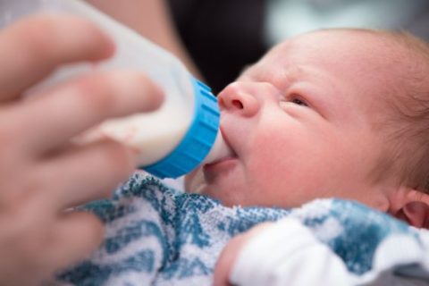 Newborn infant drinking from bottle