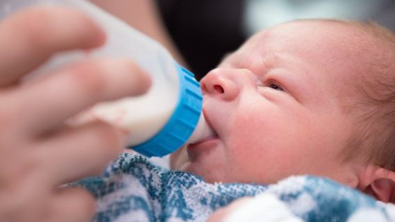 Newborn infant drinking from bottle