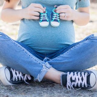 Pregnant woman holding baby shoes