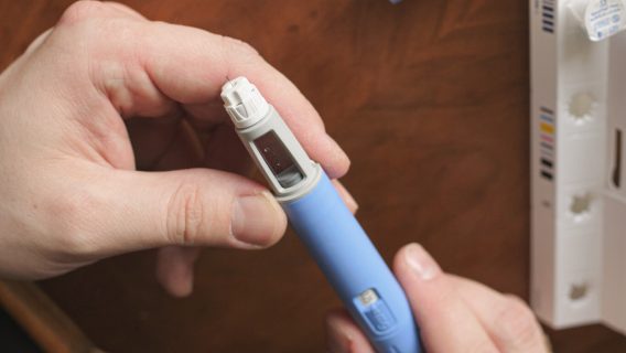 Man holding blue semaglutide pen