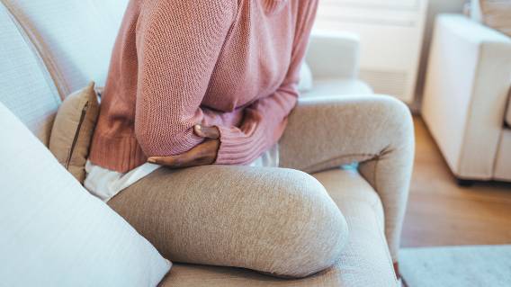 Woman on couch holds her stomach