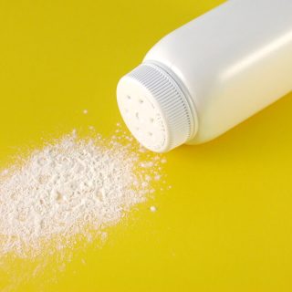 A container of spilled baby powder isolated on yellow background.