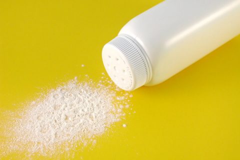 A container of spilled baby powder isolated on yellow background.