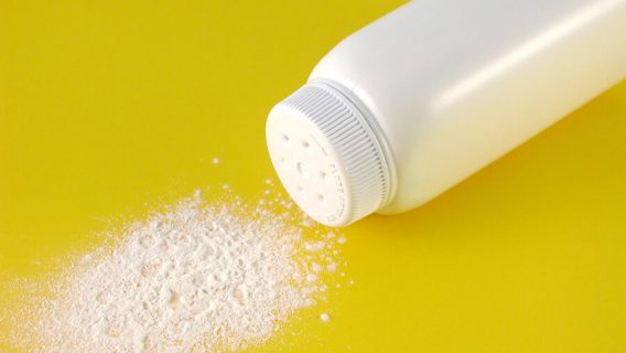 A container of spilled baby powder isolated on yellow background.