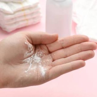 Talcum powder in woman's hand, diapers