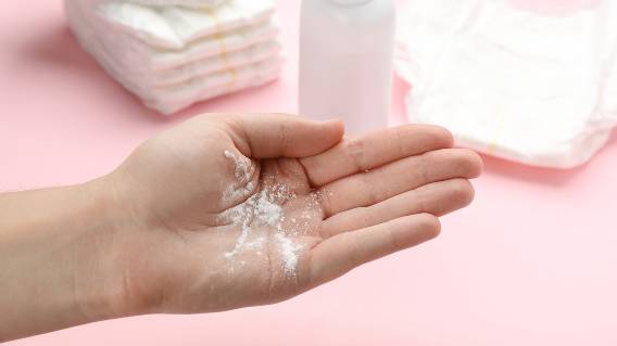 Talcum powder in woman's hand, diapers