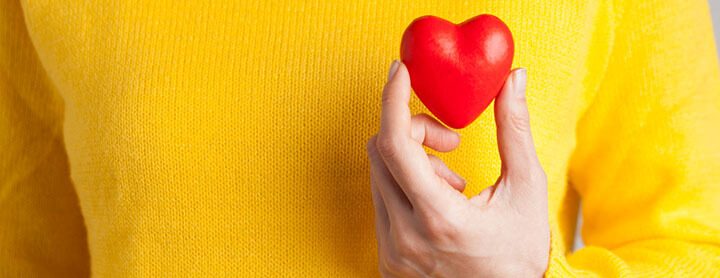 Person holding heart up to their chest