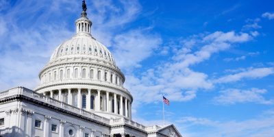 The United States Capitol building dome with an American flag against a blue sky