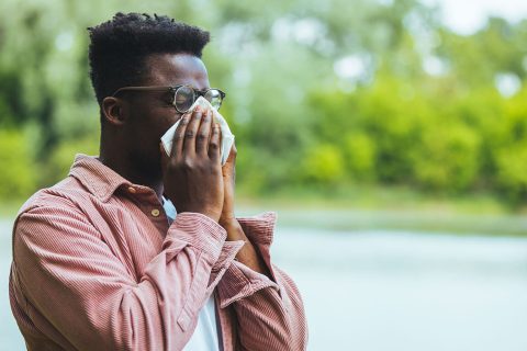 A man sneezing into a tissue.