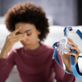Shocked Young Woman Holding CPAP Machine Mask