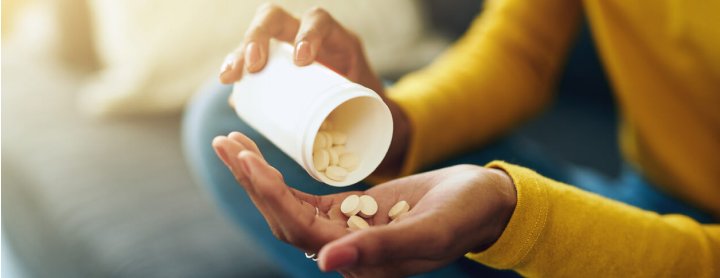 Woman pouring pills out of prescription bottle