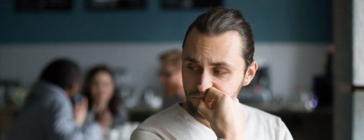 Homme assis nerveusement au café avec d'autres personnes