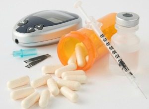 diabetes drugs prescription pills, blood sugar meter with test strips, and a syringe with insulin