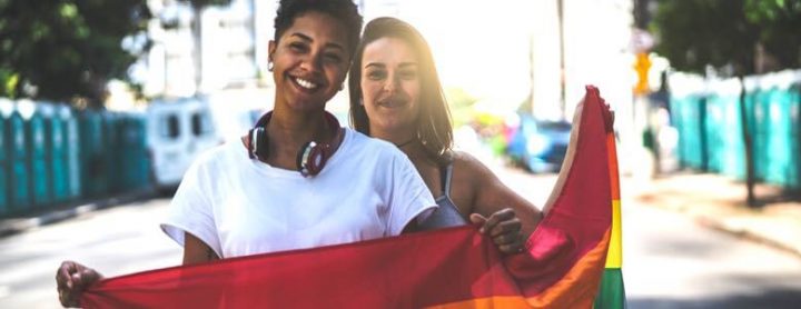lgbtq couple holding a rainbow flag